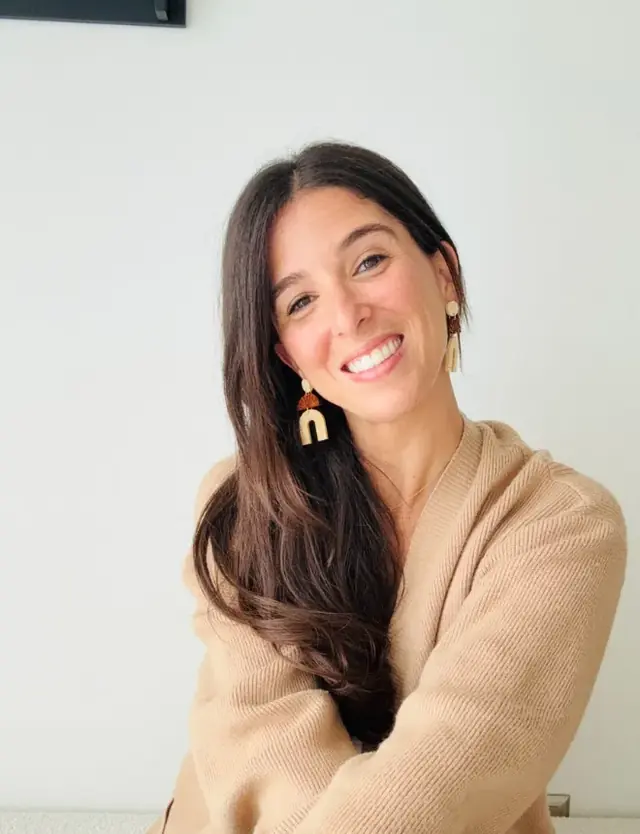 Samantha Rajchel sonriendo, con un suéter beige