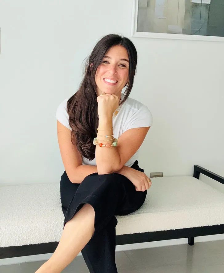 Samantha seated on a bench in a white top, listening