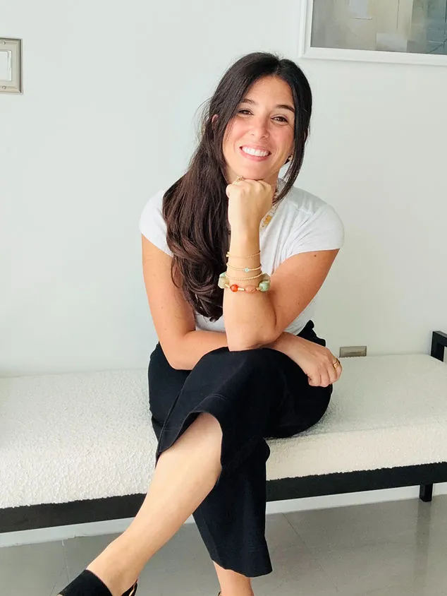 Samantha Rajchel seated on a bench in a white top, listening warmly
